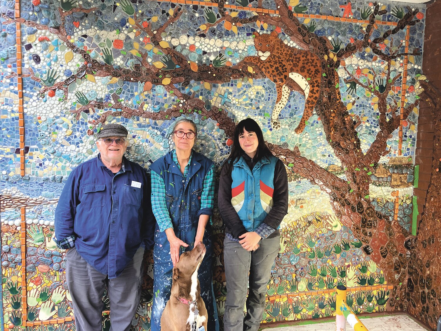 THE FINISHING TOUCHES: Peter Geisser, Mika Seeger and Jade Donaldson (from left to right) stand in front of the mural at Lippitt as it nears completion, along with Seeger’s daughter’s dog Bernie. Bernie, according to Seeger, has become a mascot for the project amongst the Lippitt students.